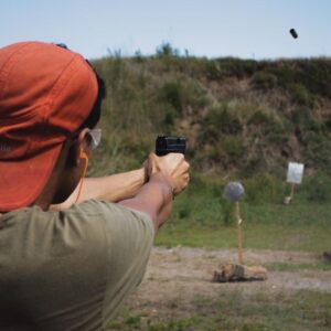 En mand skyder med pistol på en udendørs skydebane.