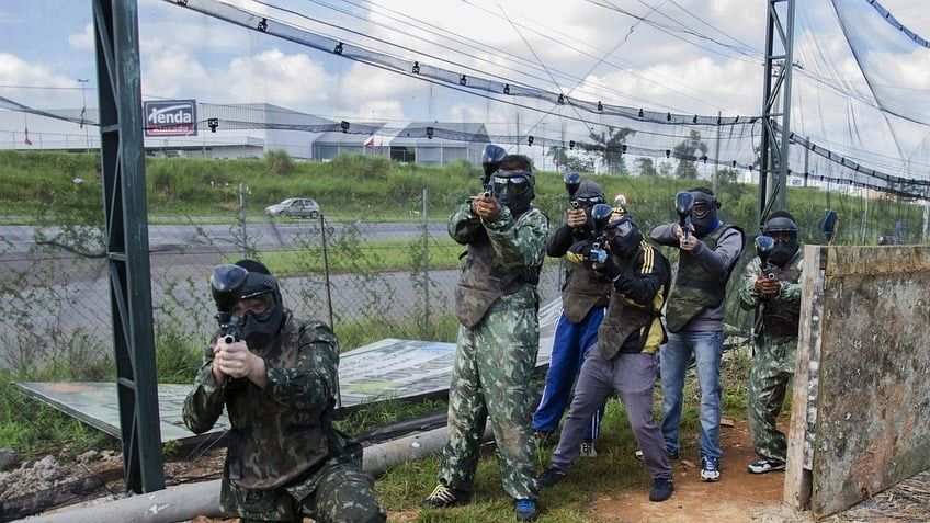 Paintballhold i camouflage sigter gennem nettet på banen