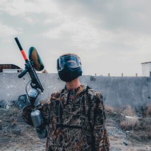 Paintballspiller med maske holder en markør på en forladt bane