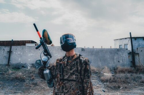 Paintballspiller med maske holder en markør på en forladt bane