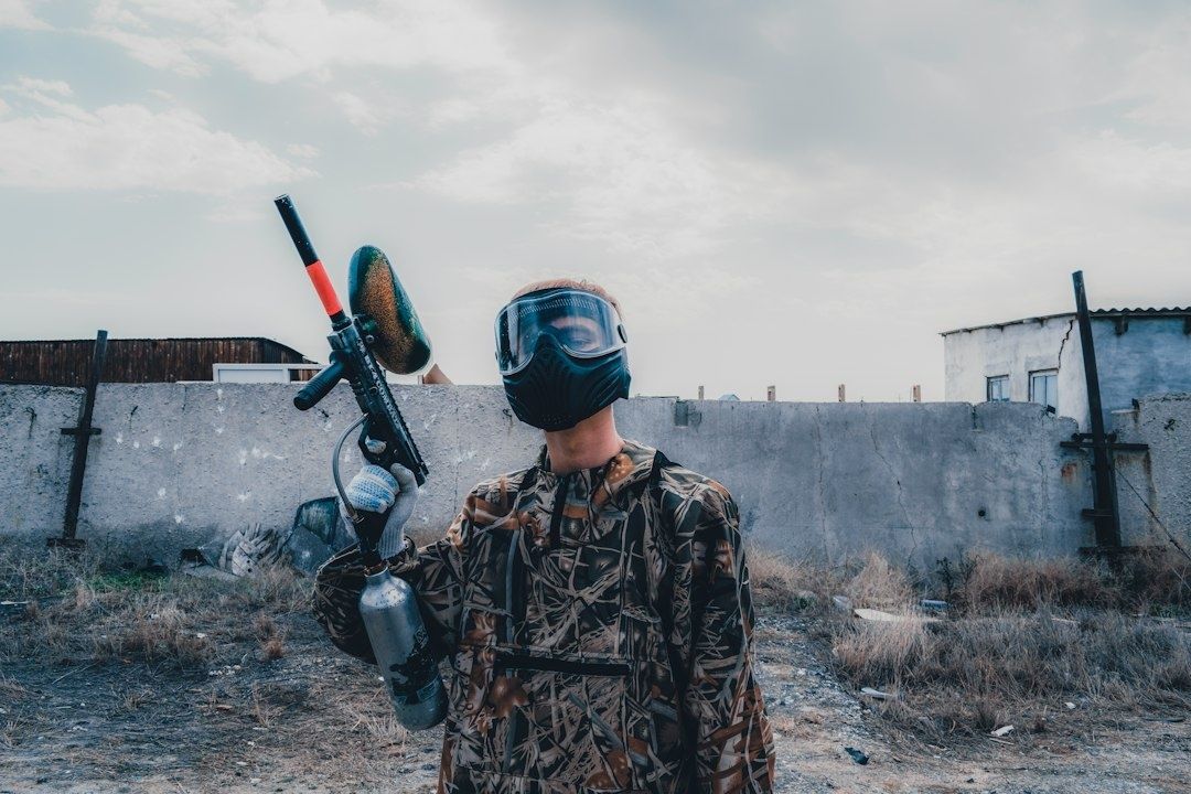 Paintballspiller med maske holder en markør på en forladt bane